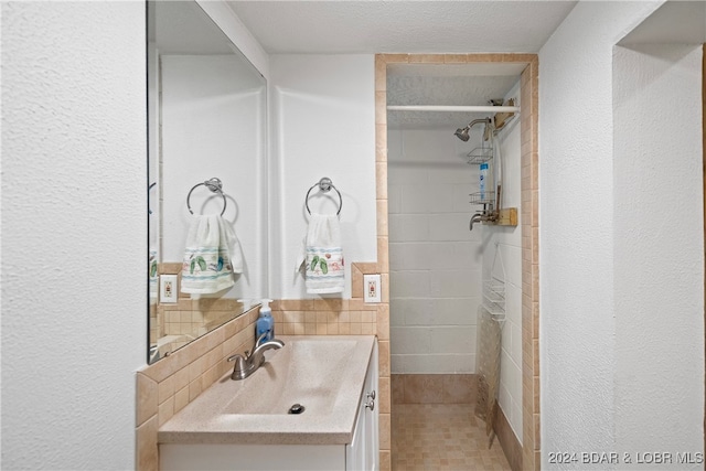 bathroom with vanity, a textured ceiling, and a tile shower