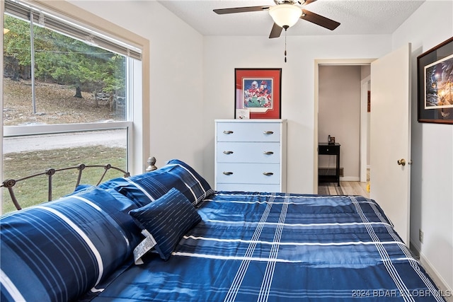 bedroom with ceiling fan, a textured ceiling, and wood-type flooring