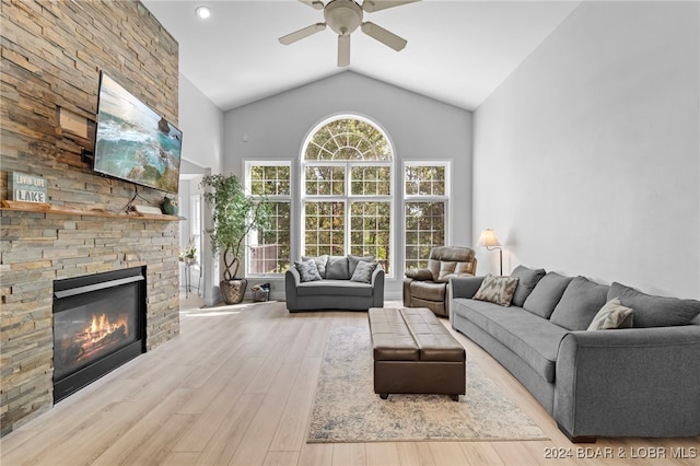 living room featuring ceiling fan, high vaulted ceiling, light hardwood / wood-style flooring, and a fireplace