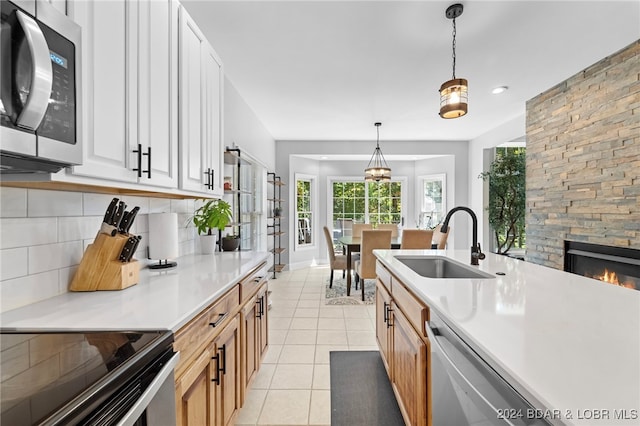 kitchen with white cabinets, backsplash, sink, pendant lighting, and stainless steel appliances