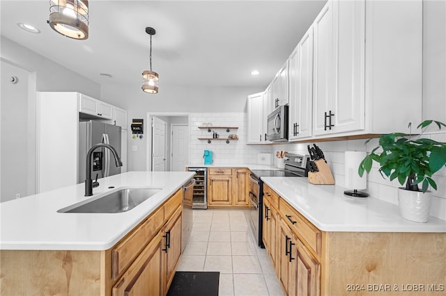 kitchen featuring appliances with stainless steel finishes, white cabinetry, sink, and a center island with sink