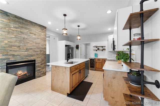 kitchen featuring tasteful backsplash, sink, an island with sink, pendant lighting, and wine cooler