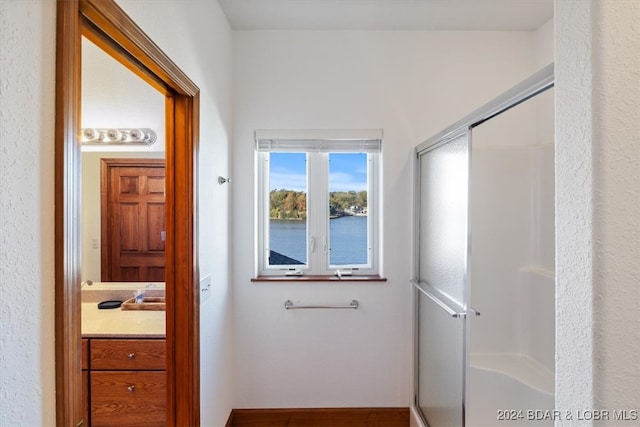 bathroom with a water view, a shower with door, and vanity