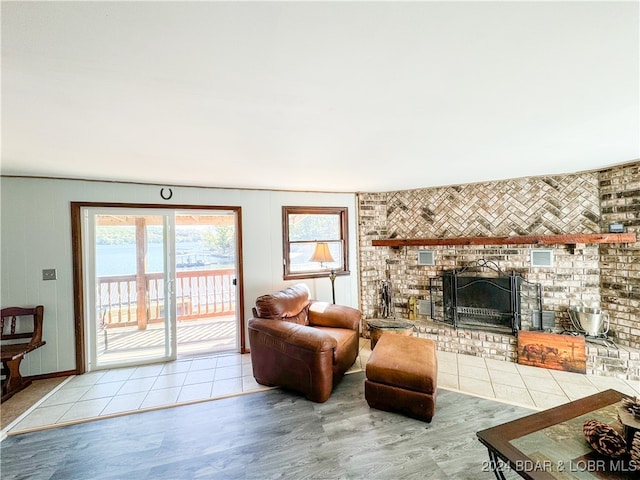 living room with a water view, light wood-type flooring, and a fireplace