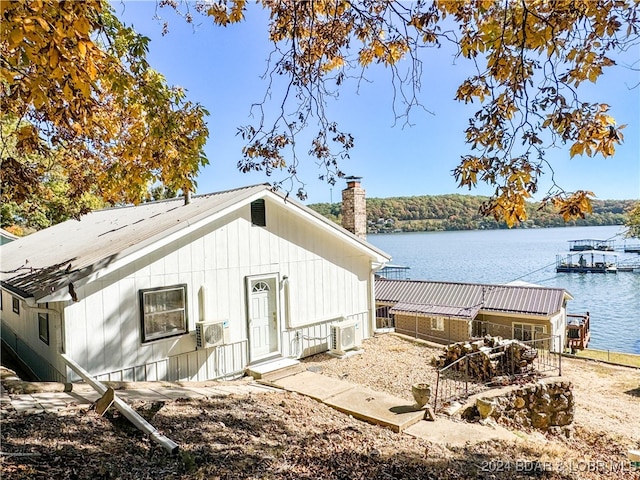 view of side of property with ac unit, a chimney, and a water view