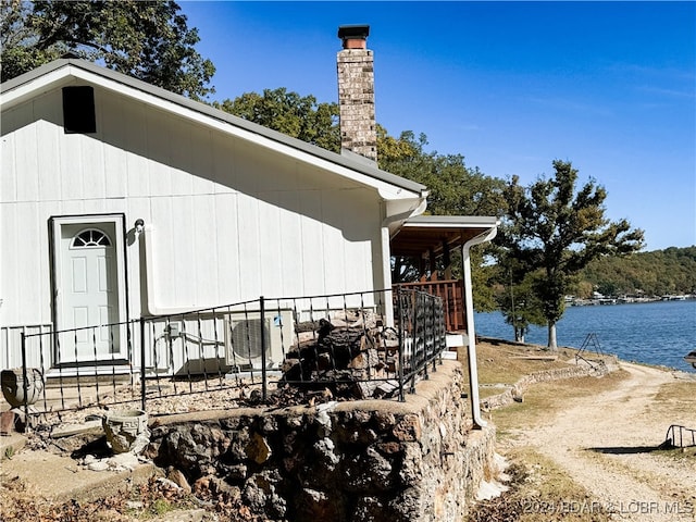 view of property exterior with a water view and a chimney