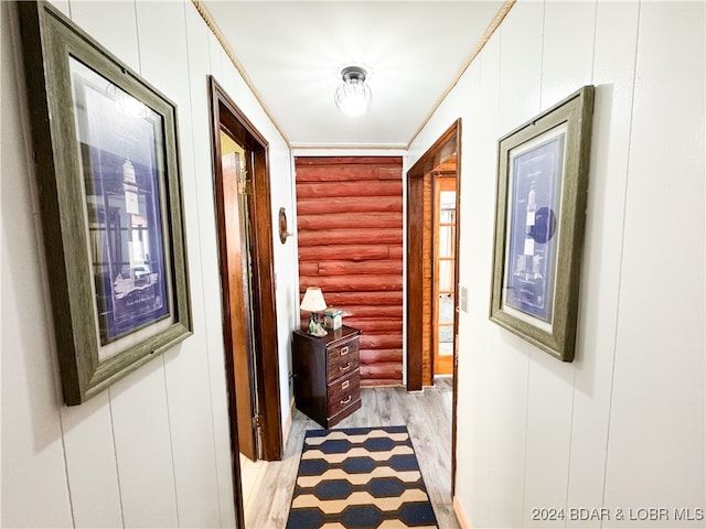 hall with light wood-style floors and log walls