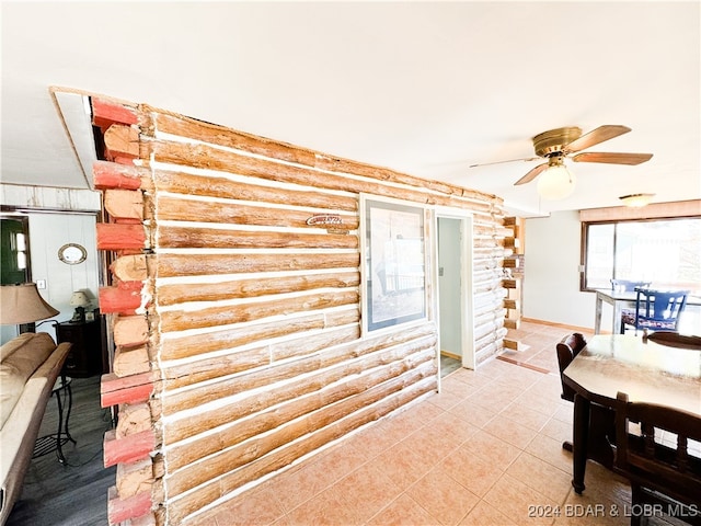 dining space featuring light tile patterned floors, log walls, and a ceiling fan