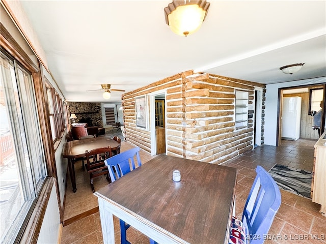 dining space featuring rustic walls, stone finish flooring, and a ceiling fan