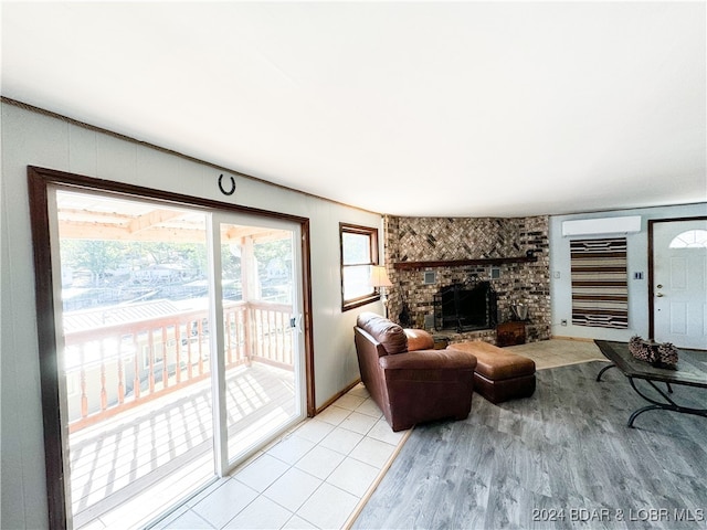 living room featuring a brick fireplace, a wall mounted air conditioner, and light wood finished floors