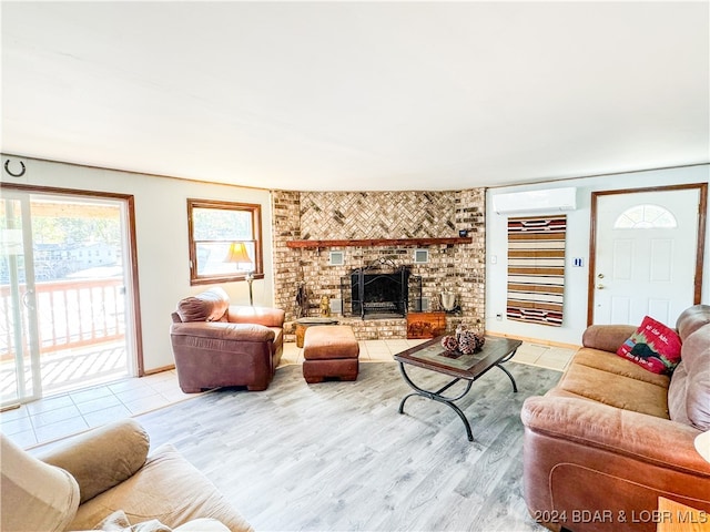 living area with a brick fireplace, light wood-style flooring, and a wall mounted AC