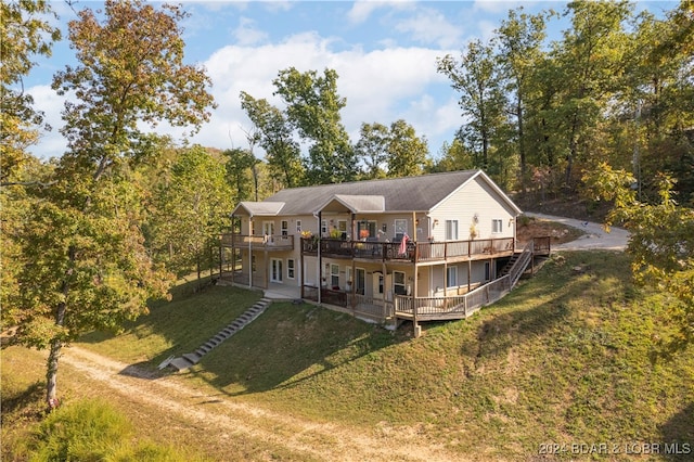 rear view of house featuring a lawn and a deck