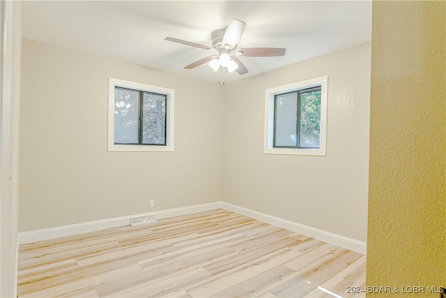 spare room with ceiling fan, light wood-type flooring, and a wealth of natural light