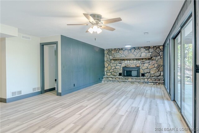 641 Porter Mill Springs Rd, Sunrise Beach, MO 65079 - unfurnished living room with light wood-type flooring, ceiling fan, a stone fireplace, and baseboards