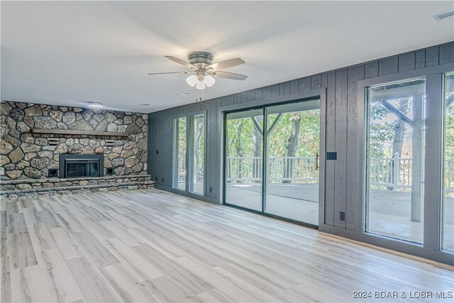 641 Porter Mill Springs Rd, Sunrise Beach, MO 65079 - unfurnished living room featuring a ceiling fan, wood finished floors, wooden walls, and a stone fireplace