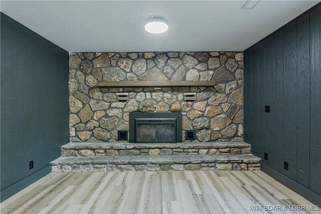 unfurnished living room with light hardwood / wood-style flooring, wooden walls, and a fireplace