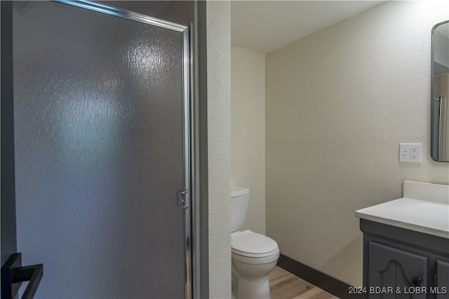 bathroom featuring toilet, a shower with shower door, hardwood / wood-style floors, and vanity