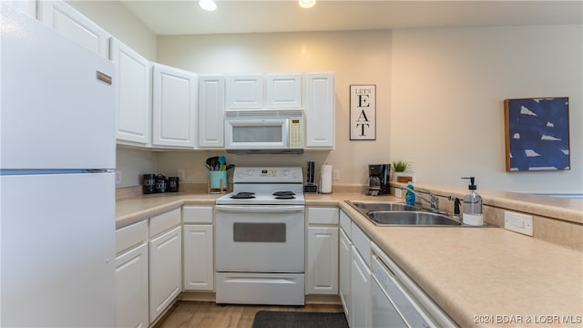 kitchen featuring sink, white cabinets, light wood-type flooring, and white appliances