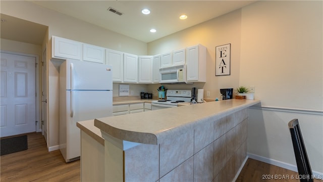 kitchen featuring white cabinets, kitchen peninsula, and white appliances