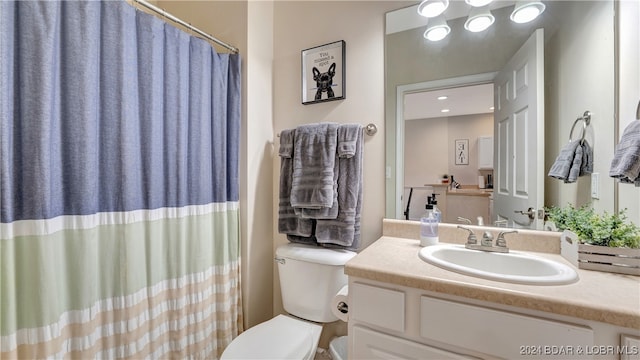 bathroom featuring toilet, curtained shower, and vanity