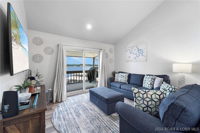 living room featuring wood finished floors, a water view, and vaulted ceiling
