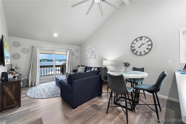 living room with hardwood / wood-style floors, a water view, high vaulted ceiling, and ceiling fan