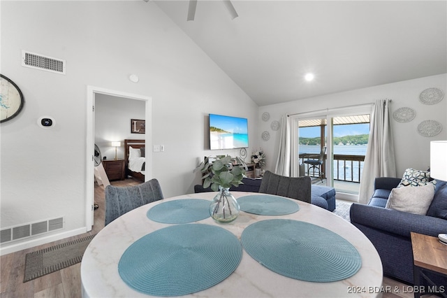 dining space featuring a water view, high vaulted ceiling, hardwood / wood-style flooring, and ceiling fan