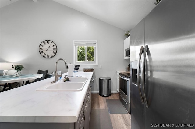 kitchen featuring a sink, appliances with stainless steel finishes, light countertops, vaulted ceiling, and dark wood finished floors