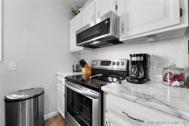 kitchen with light stone counters, white cabinetry, stainless steel appliances, and dark hardwood / wood-style floors