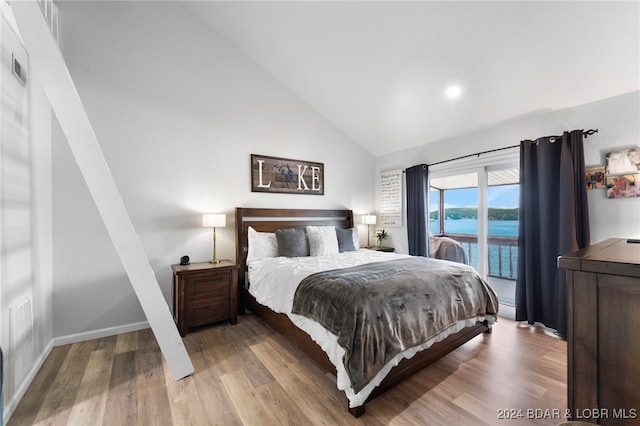 bedroom with access to outside, light wood-type flooring, a water view, and lofted ceiling