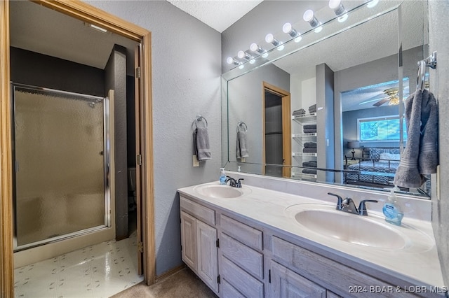 bathroom with vanity, ceiling fan, a textured ceiling, and an enclosed shower