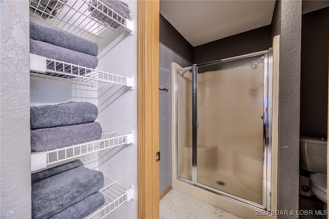 bathroom featuring toilet and a shower with door