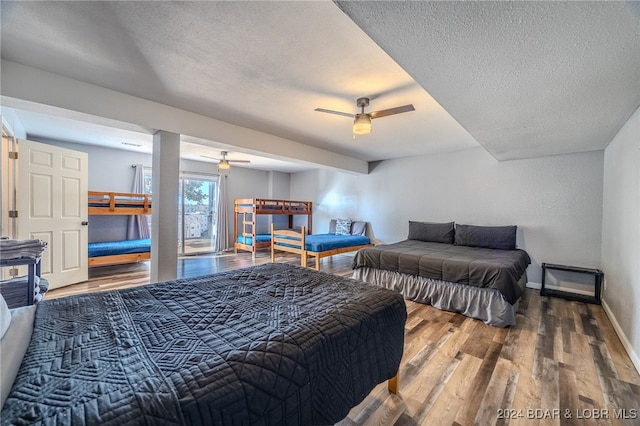 bedroom with a textured ceiling, wood-type flooring, and ceiling fan