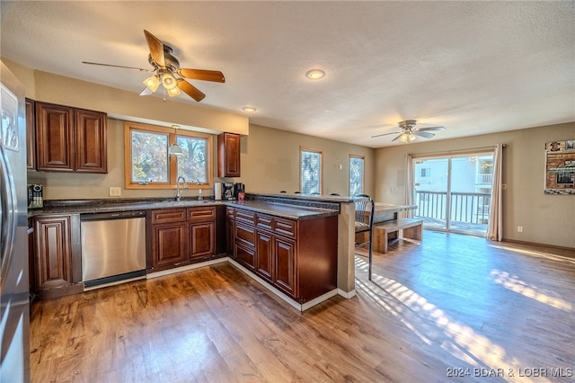 kitchen with kitchen peninsula, stainless steel dishwasher, wood-type flooring, and plenty of natural light