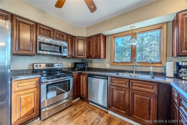 kitchen featuring hanging light fixtures, ceiling fan, light wood-type flooring, sink, and stainless steel appliances