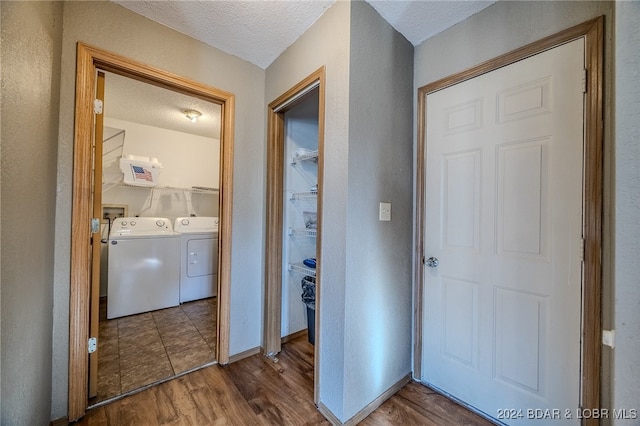 hallway featuring a textured ceiling, hardwood / wood-style flooring, and separate washer and dryer