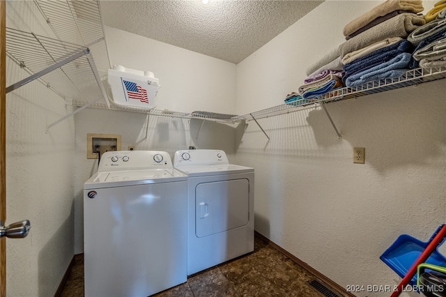 laundry area with independent washer and dryer and a textured ceiling