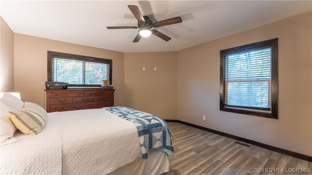 bedroom featuring hardwood / wood-style flooring, multiple windows, and ceiling fan