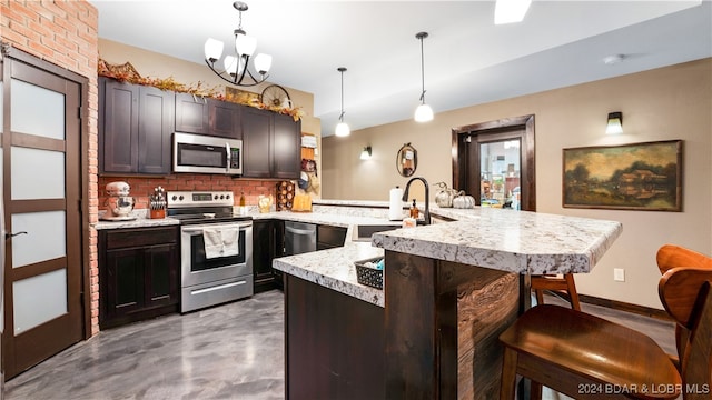 kitchen featuring appliances with stainless steel finishes, concrete floors, hanging light fixtures, and a kitchen breakfast bar