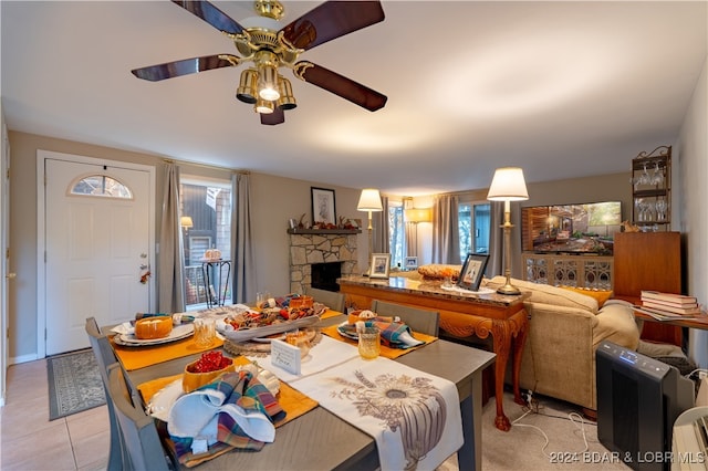 dining area featuring ceiling fan, light tile patterned flooring, and a fireplace