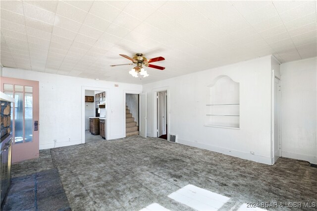 unfurnished living room with dark colored carpet and ceiling fan