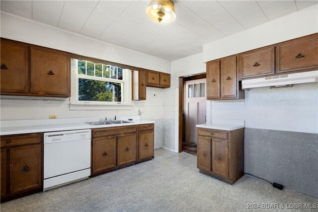 kitchen featuring white dishwasher, tile walls, and sink