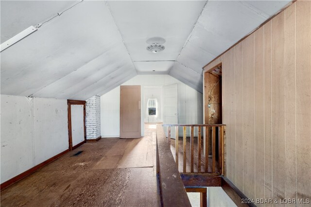 bonus room with lofted ceiling and wooden walls