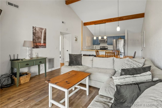 living room featuring hardwood / wood-style floors, beam ceiling, high vaulted ceiling, and sink