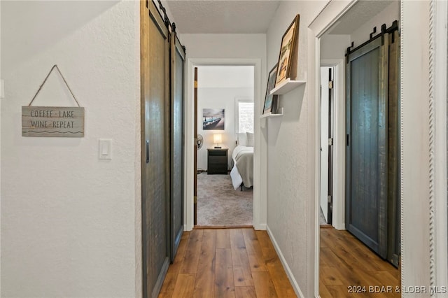 hallway featuring a textured ceiling, a barn door, and dark hardwood / wood-style floors