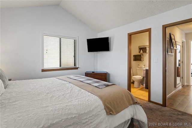 bedroom with connected bathroom, light hardwood / wood-style floors, a textured ceiling, and lofted ceiling