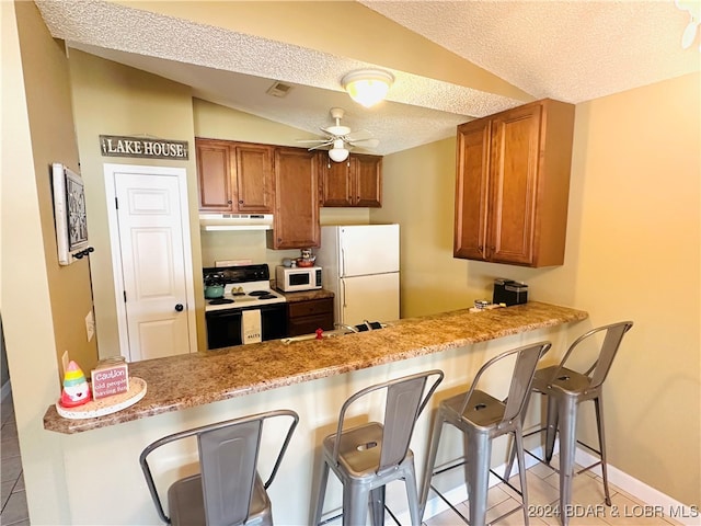 kitchen with kitchen peninsula, a breakfast bar area, ceiling fan, vaulted ceiling, and white appliances