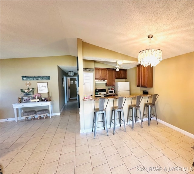 kitchen with kitchen peninsula, lofted ceiling, a kitchen breakfast bar, decorative light fixtures, and white appliances