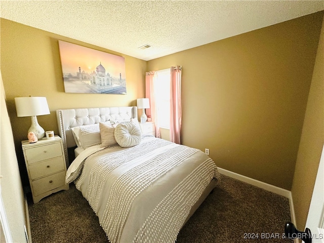 bedroom featuring a textured ceiling and dark colored carpet