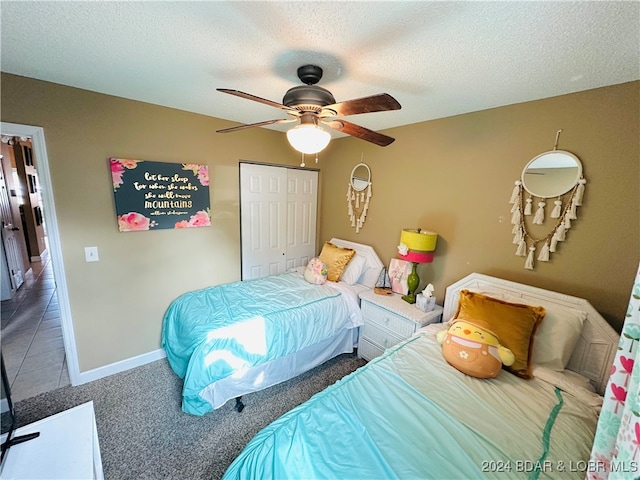 carpeted bedroom featuring a closet, ceiling fan, and a textured ceiling